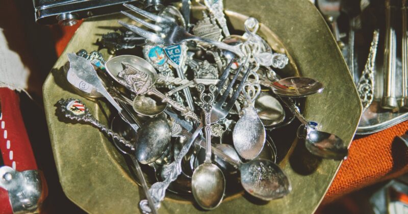 Metal bowl overflowing with assorted vintage silver spoons and forks.