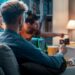 People on a sofa watching TV together, one holds a remote while a streaming service fills the screen.