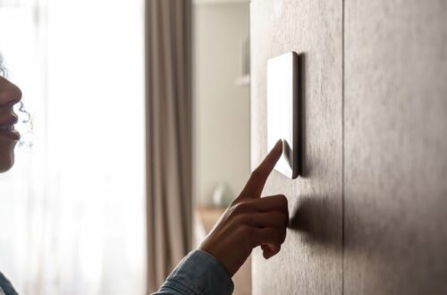 A young woman touching a screen on the wall of her home. The screen controls energy efficiency in the house.