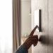 A young woman touching a screen on the wall of her home. The screen controls energy efficiency in the house.