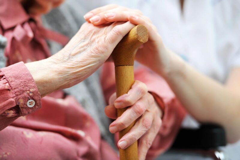 aging hands and a young hands on a cane