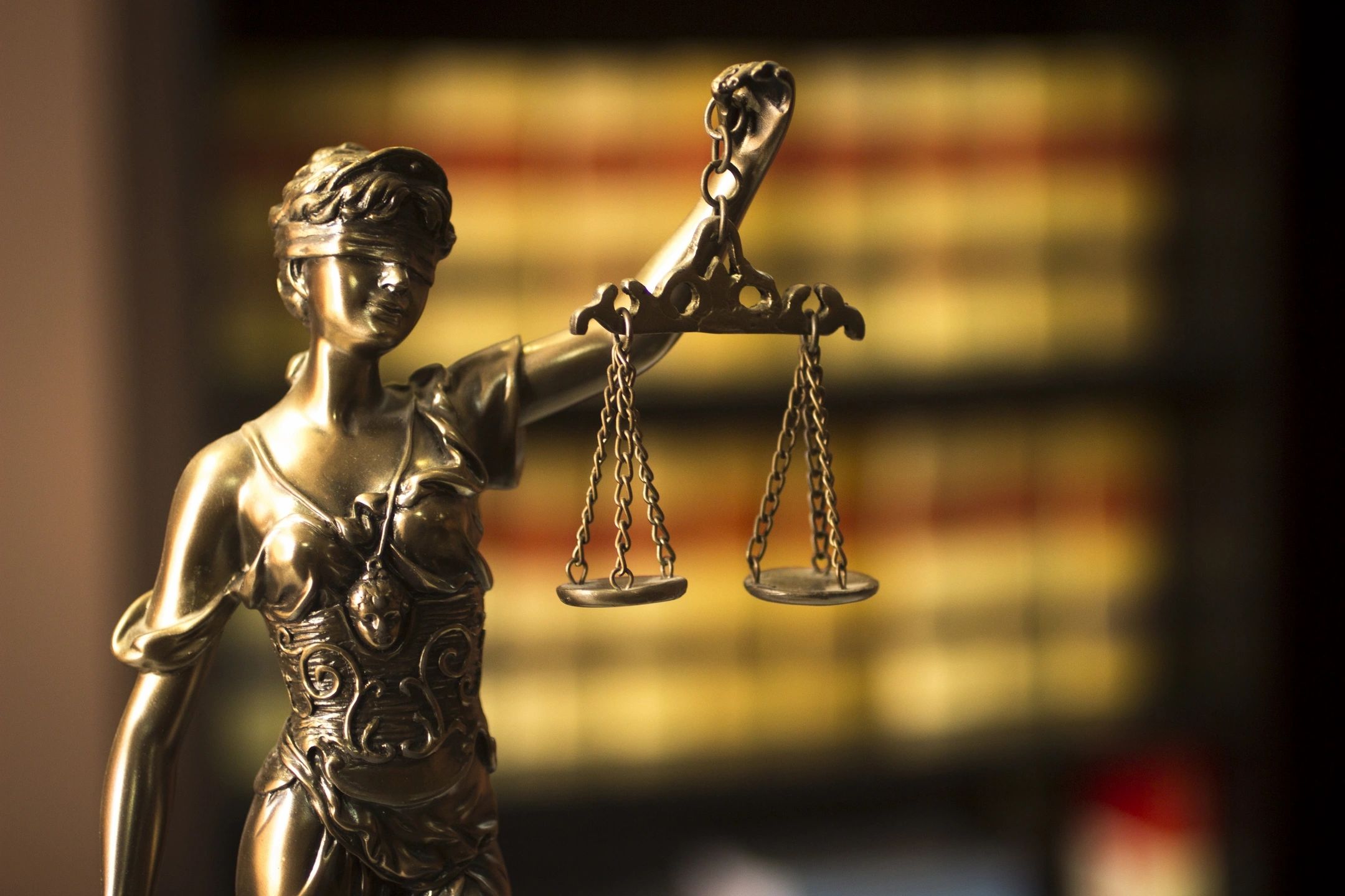 Workers compensation Blindfolded statue of Lady Justice holding the scales of justice on a dark background (close-up).