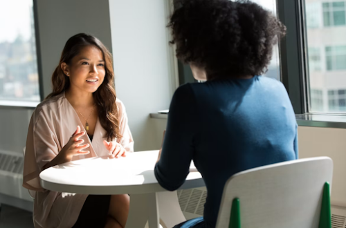 2 women sitting at a table.Difficult Conversations