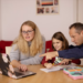 Family sitting around a laptop at the kitchen table. Family debt