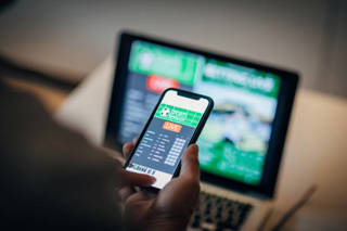 Mature man using mobile app for live betting and online gambling and watching a sports match Informed wagers
