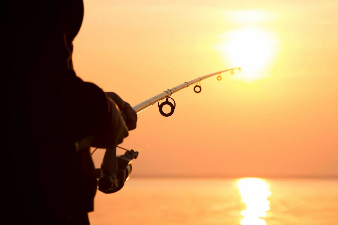 Person fishing with a sunrise background